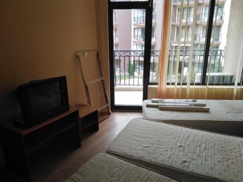 a room with two beds and a television and a balcony at Апартамент Попов in Sunny Beach