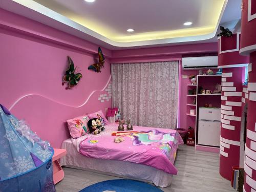 a pink room with a bed with two dolls on it at Kenting Mola in Nanwan