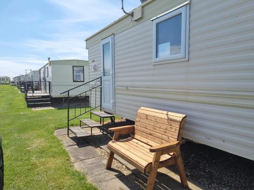 a wooden bench sitting on the side of a trailer at Caravan Holiday home Happy days south 17 in Chapel Saint Leonards