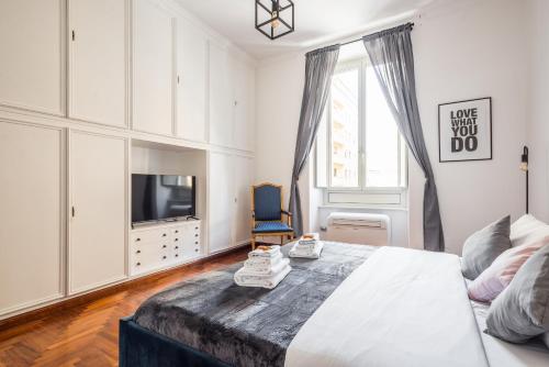 a white bedroom with a bed and a tv at Appartamento Principe Amedeo in Rome