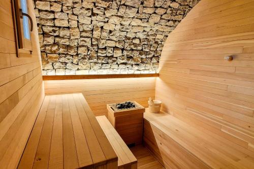 a sauna with a stone wall and a bench at Narciso Home in Adrara San Rocco