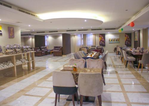 The Saj Hotel في عجمان: مطعم فيه طاولات وكراسي في الغرفة