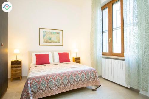 - une chambre avec un lit doté d'oreillers rouges et une fenêtre dans l'établissement A Casa Di Rosa, à Migliarino