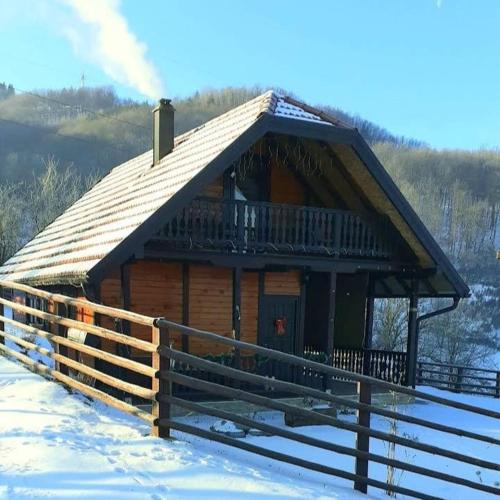 a log cabin with a deck in the snow at Brvnara Sofiana in Bajina Bašta