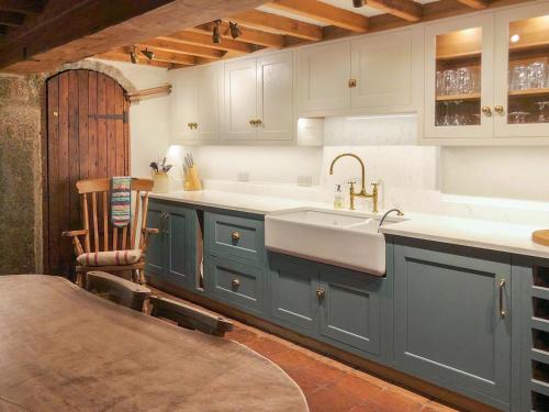 a kitchen with blue cabinets and a sink and a chair at Warmhill Farmhouse in Hennock