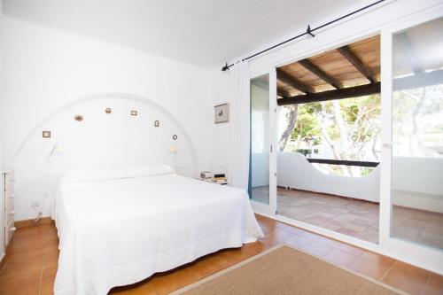 a bedroom with a white bed and a large window at Voramar Ham in Playa de Muro