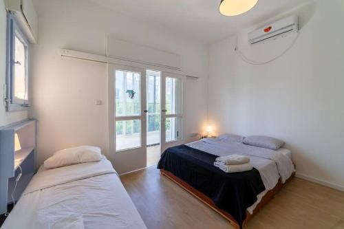 een slaapkamer met 2 bedden en een raam bij Large 3 bedrooms a block from the beach in Tel Aviv