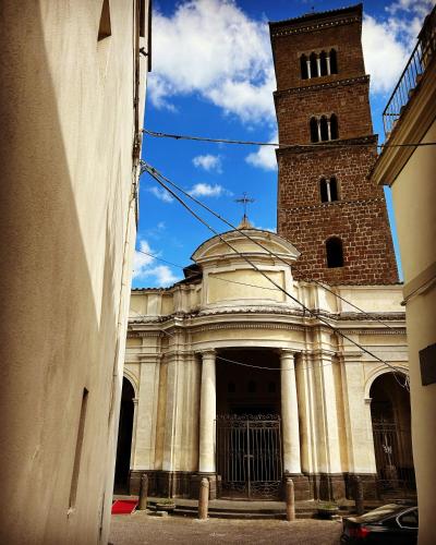 a church with a tall tower and a clock at Relais il Duomo con SPA privata in Sutri