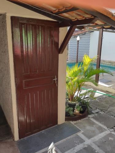 una puerta de madera de una casa con plantas en kitnet A com piscina, en Arraial do Cabo