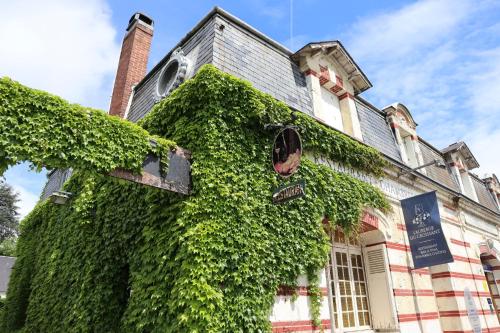 an ivy covered building with a sign on it at L'Auberge du Croissant in Rochecorbon