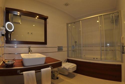 uma casa de banho com um chuveiro, um lavatório e uma banheira em Small Beach Hotel em Turgutreis