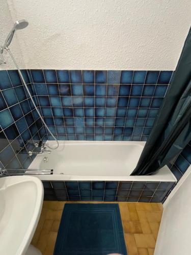 a bathroom with a tub and a toilet and blue tiles at Chez Edgar in Thollon
