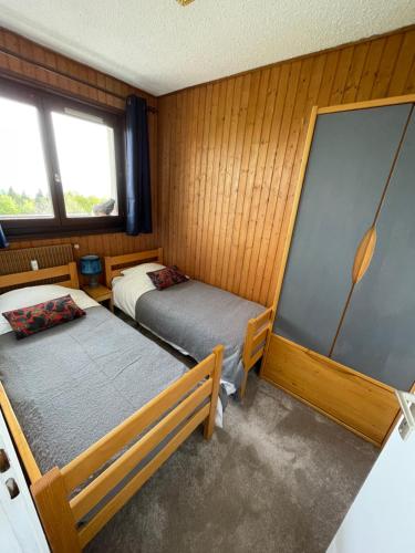 two beds in a room with wooden walls and windows at Chez Edgar in Thollon