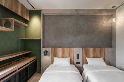 two beds in a room with green walls at ShanHeShu Homestay in Hualien City
