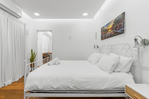 a white bedroom with a white bed with white pillows at Brown suite in Tel Aviv