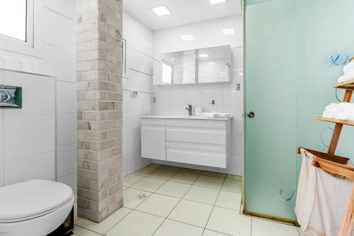 a white bathroom with a toilet and a sink at Brown suite in Tel Aviv