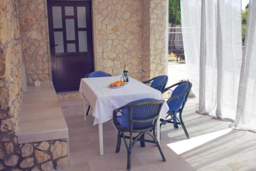 stół z niebieskimi krzesłami i butelkę wina w obiekcie TEODORA - kamenný domek 300 m od moře w Novalji