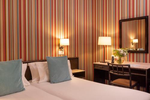 a hotel room with a bed and a desk with a mirror at Hotel Clément in Paris