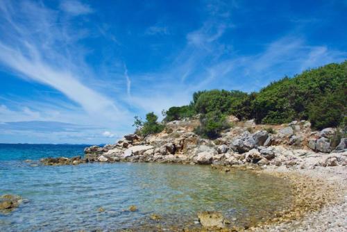 uma praia com pedras e o oceano num dia ensolarado em TEODORA - kamenný domek 300 m od moře em Novalja