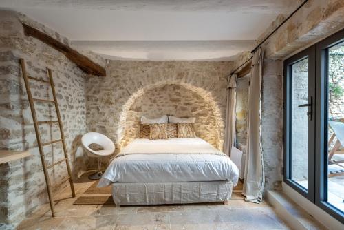 a bedroom with a bed and a stone wall at La Grange de la Chèvre d'Or in Lagnes