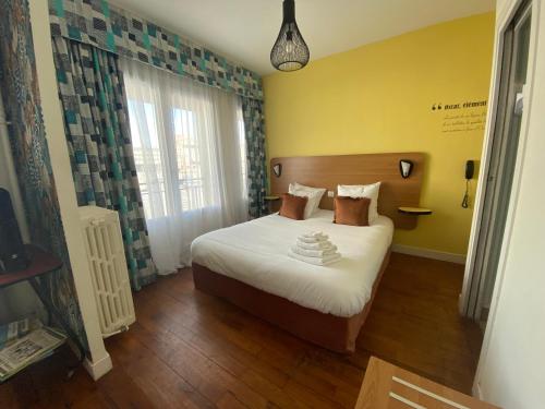 a bedroom with a bed in a room with yellow walls at Oscar Hôtel Le Havre Centre in Le Havre