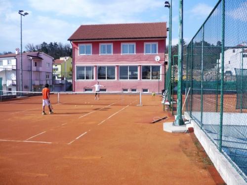 two people playing tennis on a tennis court at Apartments Villa Bare in Kastav