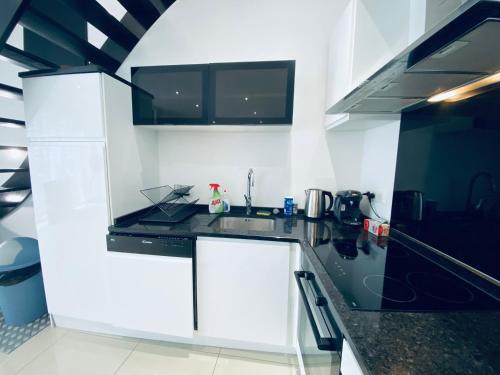 une cuisine avec des armoires blanches et des comptoirs noirs dans l'établissement Maison Hypercentre - Duplex - Cozy houses, à Reims