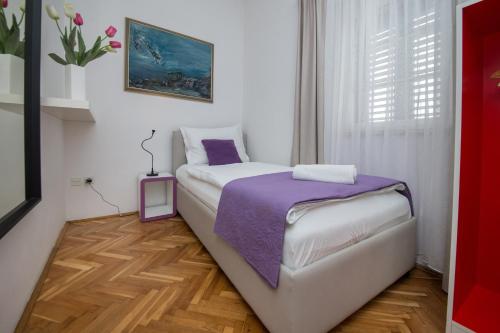 a small bedroom with a bed with a purple blanket at Pansion Kamenar in Primošten