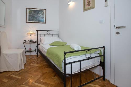 a bedroom with a bed with a green comforter at Pansion Kamenar in Primošten