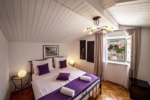 een slaapkamer met een groot bed met paarse kussens bij Pansion Kamenar in Primošten