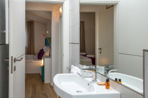 een badkamer met een wastafel en een spiegel bij Pansion Kamenar in Primošten