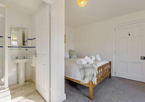 una camera bianca con letto e lavandino di Helebridge House a Marhamchurch