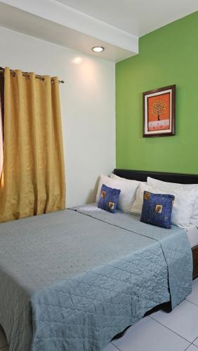 a bedroom with a bed with blue sheets and green walls at 20 Studio Hotel in Marikina