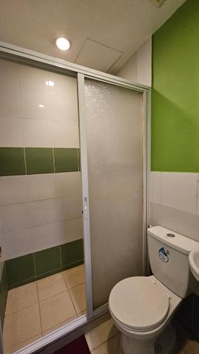 a bathroom with a toilet and a sliding shower door at 20 Studio Hotel in Marikina