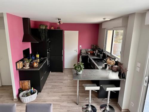 une cuisine avec des comptoirs noirs et des murs roses dans l'établissement Maison proche circuit des 24h, au Mans