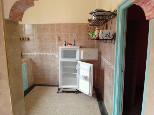 a small kitchen with a white refrigerator in a room at aglou plage in Tiznit