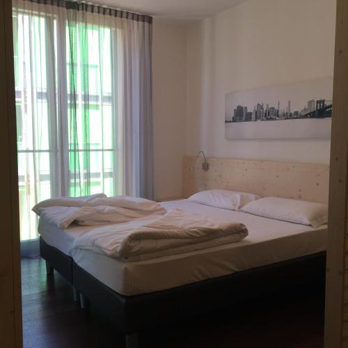 a large bed in a room with a window at Komodo short stay apartments in Trento