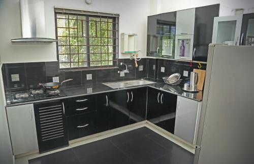 特里凡得琅的住宿－AASTHA，厨房配有黑色柜台和白色冰箱。