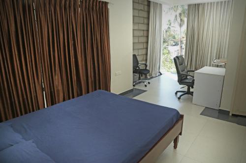 a bedroom with a bed and a desk and chairs at AASTHA in Trivandrum