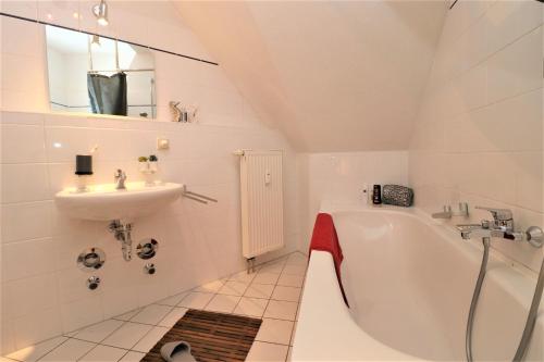 a white bathroom with a sink and a tub and a sink at Wohnpark Schmiedestraße App 03 in Wustrow