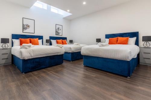three beds with orange pillows in a room at Water Street by Ustay Aparthotels in Liverpool