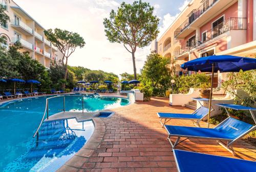 a swimming pool with chairs and umbrellas next to a building at Hotel San Valentino Terme in Ischia