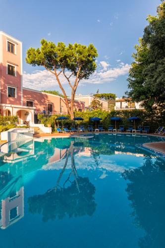 a large swimming pool with chairs and a tree at Hotel San Valentino Terme in Ischia