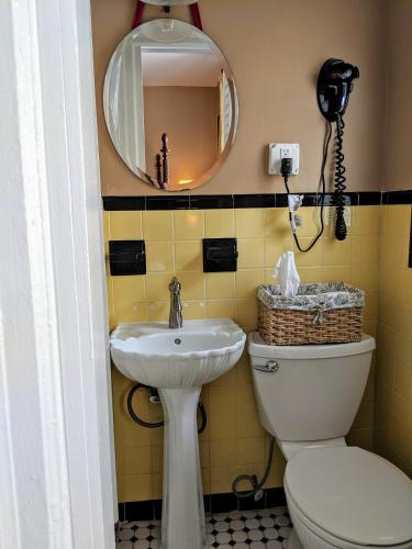 a bathroom with a sink and a toilet and a mirror at Chelsea Pub and Inn in Atlantic City