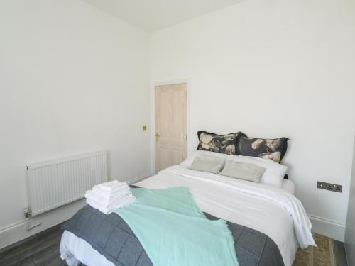 biała sypialnia z łóżkiem z niebieskim kocem w obiekcie The Annex w mieście Exeter