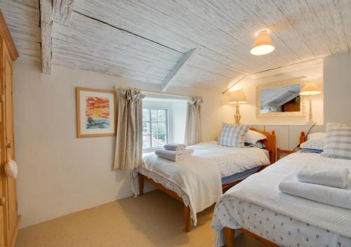 a bedroom with two beds and a window at Rose Cottage in Helford