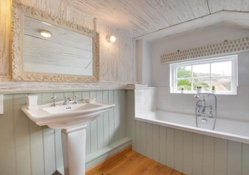 a white bathroom with a sink and a bath tub at Rose Cottage in Helford