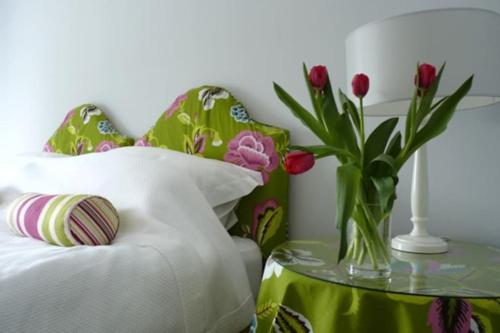 a vase of flowers on a table next to a bed at The Cowshed in Laurencekirk