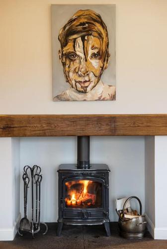 a painting of a woman is above a fireplace at The Cowshed in Laurencekirk