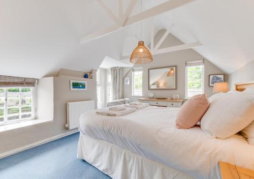 a large white bedroom with a large bed and windows at Well Too in Helford
